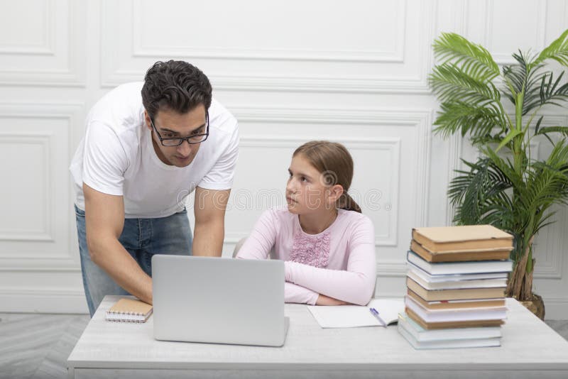 Tatăl și fiica studiind împreună online la domiciliu. El explica lecția și ea îl ascultă cu atenție stock photo