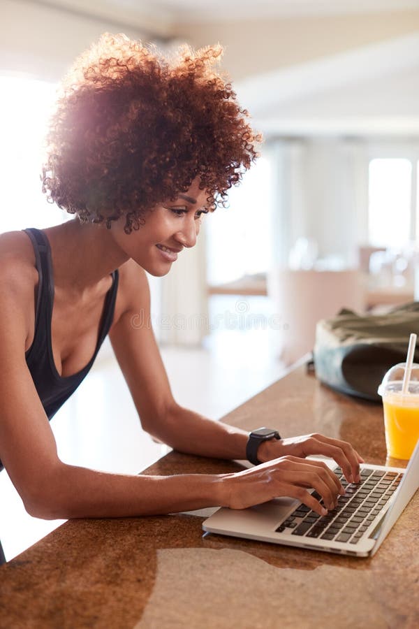 Tausendjährige Afroamerikanerfrau unter Verwendung des Laptops, zum von Eignungsdaten nach ihr zu überprüfen arbeiten aus, vertik stockfotos