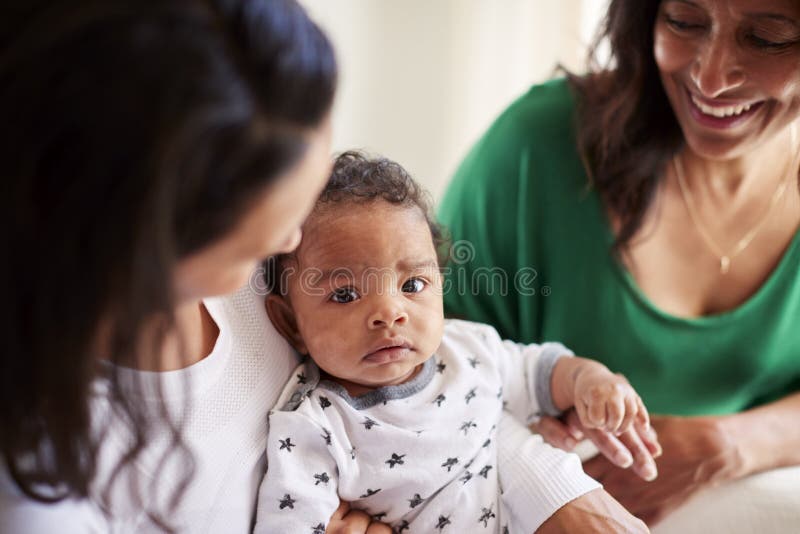 Tausendjährige Afroamerikanermutter, die ihren dreimonatigen alten Babysohn, ihre Mutter neben ihnen, nah oben hält lizenzfreie stockfotos