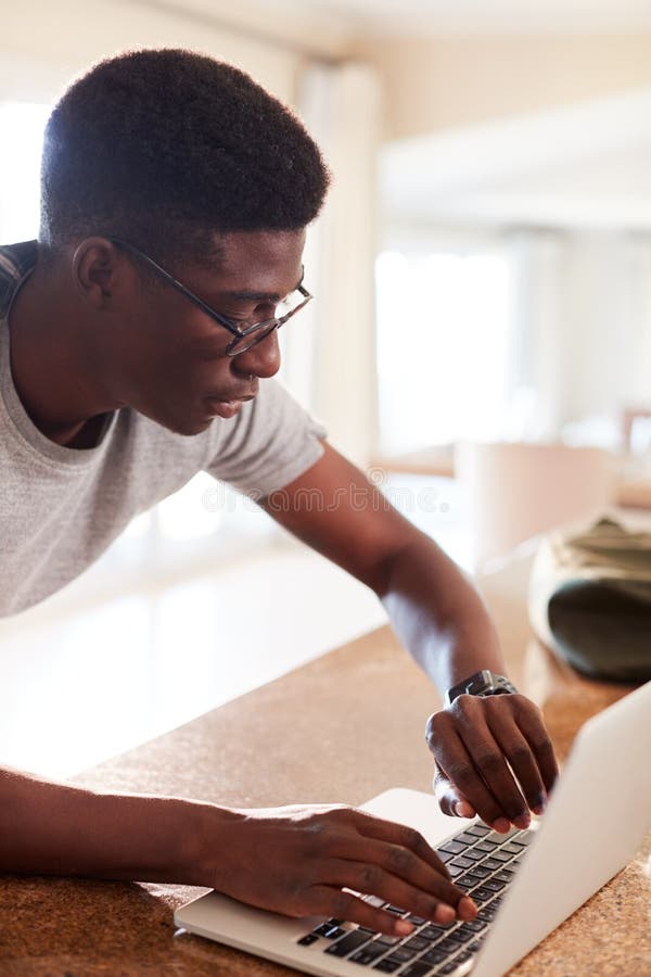 Tausendjähriger Afroamerikanermann, der zu Hause Eignung App auf smartwatch unter Verwendung des Laptops nach Turnhalle, Vertikal lizenzfreie stockfotografie