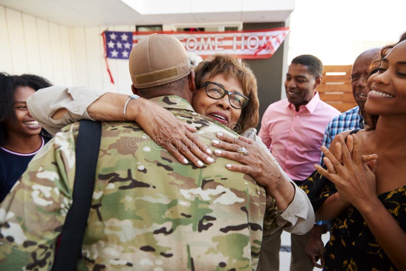 Tausendjähriger Afroamerikanersoldat, der nach Hause zu seiner Familie, Großmutter umfassend, hintere Ansicht zurückkommt lizenzfreies stockfoto