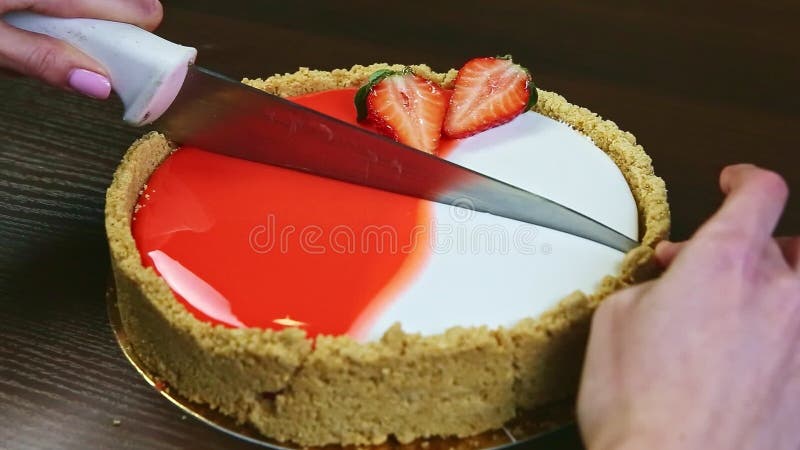Taux de confiseur de gros plan sur la moitié du gâteau au fromage vitré par couteau avec les fraises en tranches banque de vidéos