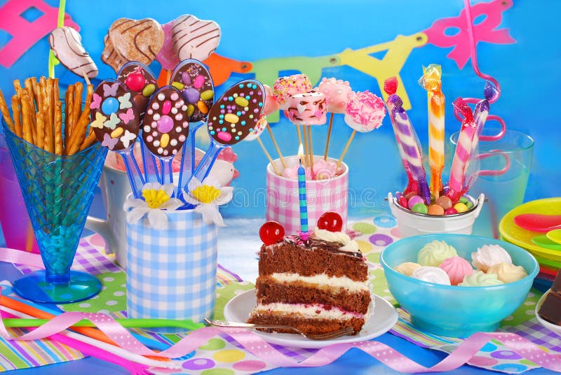 Bambini e decorazioni di compleanno. ragazzi e ragazze a tavola con cibo,  dolci, bevande e gadget per le feste.