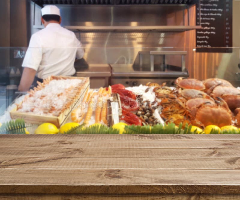 Tavola di legno e vista vaga sugli scaffali dei frutti di mare in ristorante fotografie stock Tavola di legno e vista vaga sugli scaffali dei frutti di mare in ristorante fotografie stock
