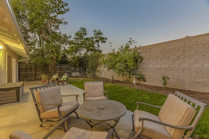 Tavola rotonda e poltrone attenuate sul patio di una casa fotografie stock libere da diritti Tavola rotonda e poltrone attenuate sul patio di una casa fotografie stock libere da diritti