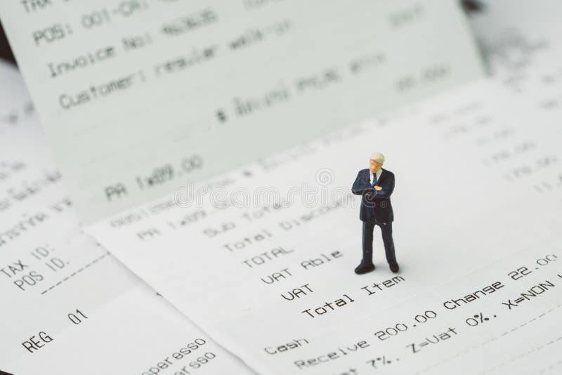 Tax, accounting and business expenses concept, miniature businessman figure standing on printed payment invoice or receipt around royalty free stock photos Tax, accounting and business expenses concept, miniature businessman figure standing on printed payment invoice or receipt around royalty free stock photos