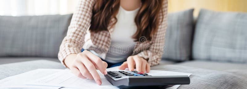 Tax day coming concept. Hands of an working accountant using a calculator. Documents, charts around. In the top of a wooden office desk