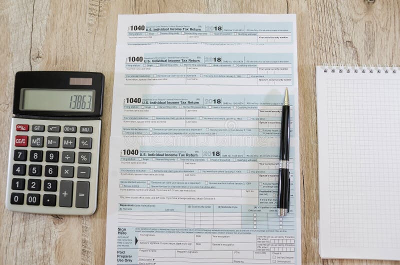 Tax Forms 1040, Calculator, Notebook and Pen on the Table. View from