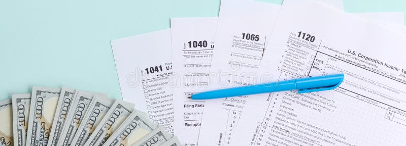 Tax forms lies near hundred dollar bills and blue pen on a light blue background. Income tax return royalty free stock photography Tax forms lies near hundred dollar bills and blue pen on a light blue background. Income tax return royalty free stock photography
