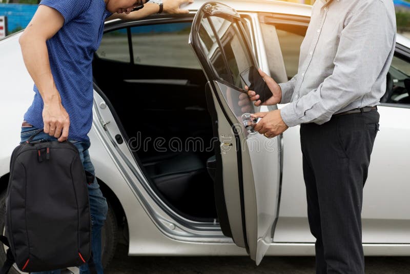 Taxi driver greeting his passengers with their luggage on the si