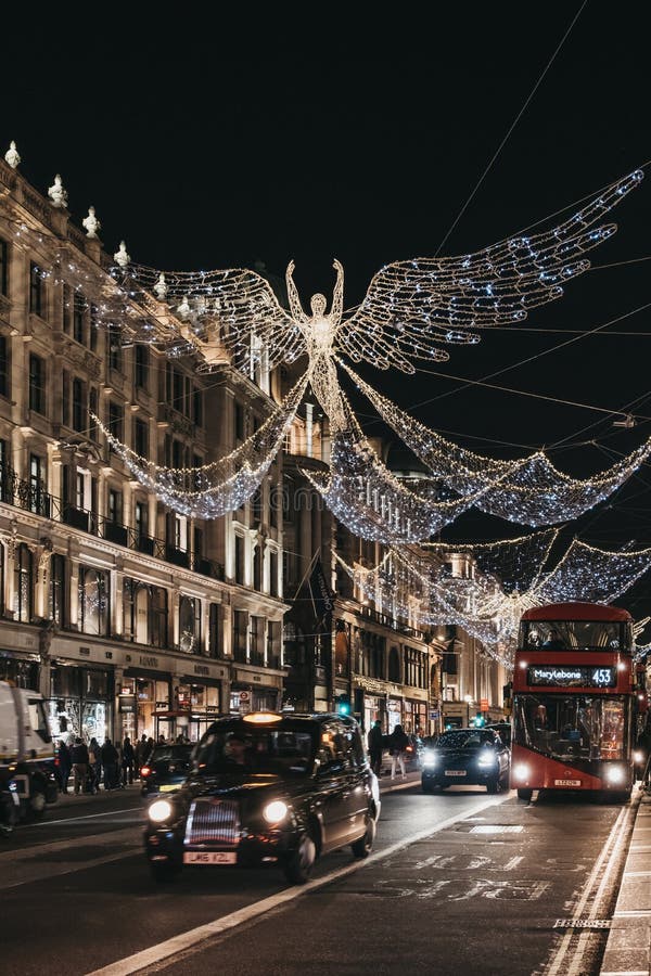 Taxis and buses under angel Christmas lights on Regent Street, London, UK, in the evening, motion blur