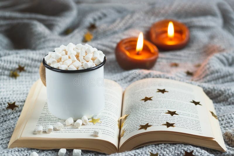 Taza blanca con cacao y la melcocha en un libro abierto en un CCB texturizado gris claro foto de archivo Taza blanca con cacao y la melcocha en un libro abierto en un CCB texturizado gris claro foto de archivo