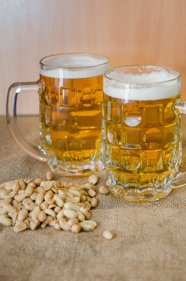 Taza con la cerveza y los cacahuetes salados en la tabla foto de archivo Taza con la cerveza y los cacahuetes salados en la tabla foto de archivo