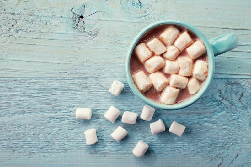 Blue cup of hot cocoa with marshmallows on blue wooden background. Blue cup of hot cocoa with marshmallows on blue wooden background