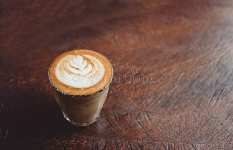 Taza de café ascendente cercana con arte del latte en la tabla de madera del grunge en el café fotos de archivo Taza de café ascendente cercana con arte del latte en la tabla de madera del grunge en el café fotos de archivo