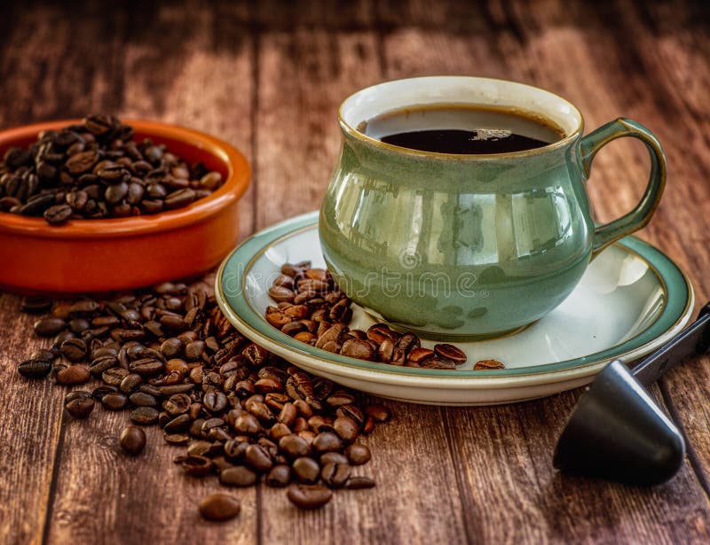 Green Coffee cup and saucer close-up over dark roasted coffee beans on wooden table. Green Coffee cup and saucer close-up over dark roasted coffee beans on wooden table