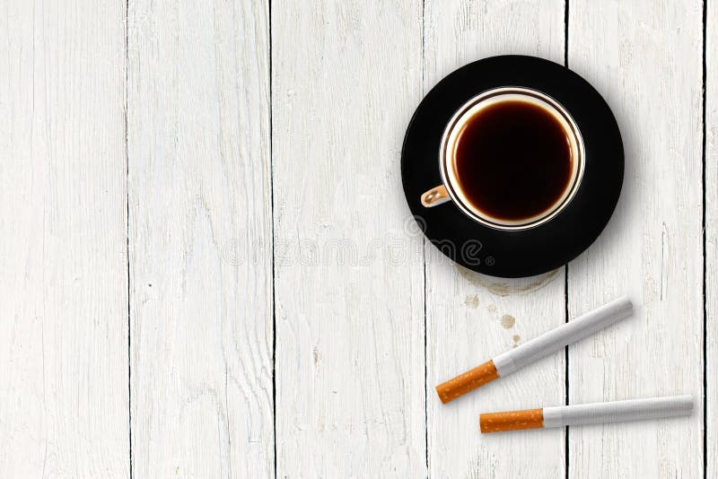 Cup of coffee with cigarettes on the wooden plank table. Cup of coffee with cigarettes on the wooden plank table