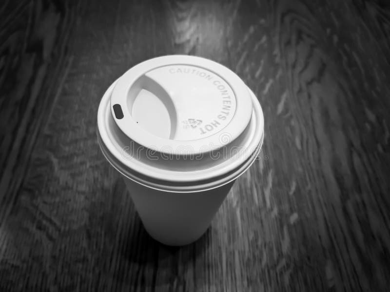 Taza de café disponible hecha del plástico y del papel, en una superficie de sobremesa de madera fotografía de archivo libre de regalías Taza de café disponible hecha del plástico y del papel, en una superficie de sobremesa de madera fotografía de archivo libre de regalías