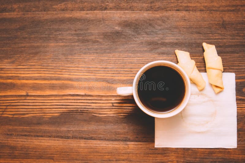 Taza de café en una servilleta blanca con las galletas en un fondo de madera imagenes de archivo Taza de café en una servilleta blanca con las galletas en un fondo de madera imagenes de archivo