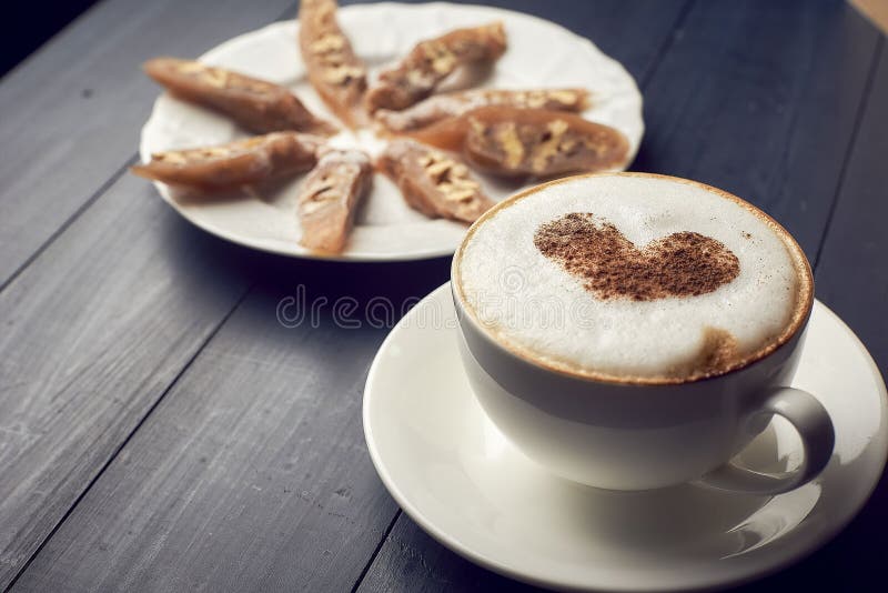 Taza de capuchino con arte hermoso del latte del corazón en la tabla de madera cerca de la placa con el postre estilo plano de la fotografía de archivo libre de regalías Taza de capuchino con arte hermoso del latte del corazón en la tabla de madera cerca de la placa con el postre estilo plano de la fotografía de archivo libre de regalías