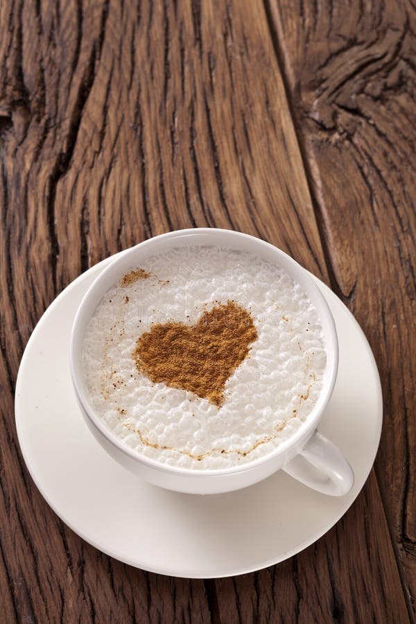 Taza de capuchino con canela en polvo bajo la forma de corazón. fotos de archivo Taza de capuchino con canela en polvo bajo la forma de corazón. fotos de archivo
