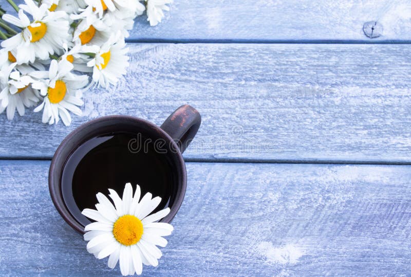 Taza de t? de manzanilla con un ramo de margaritas en un fondo azul de madera imágenes de archivo libres de regalías Taza de t? de manzanilla con un ramo de margaritas en un fondo azul de madera imágenes de archivo libres de regalías