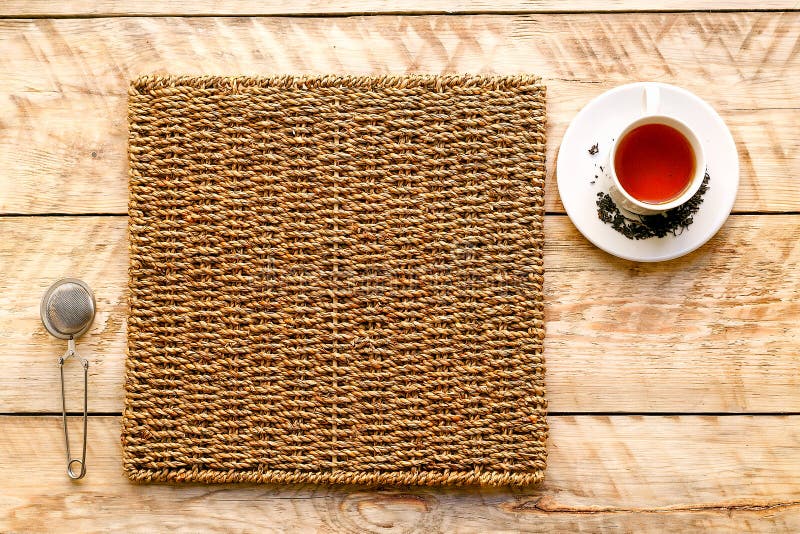 Taza de té en una estera de mimbre con el tamiz fotografía de archivo Taza de té en una estera de mimbre con el tamiz fotografía de archivo