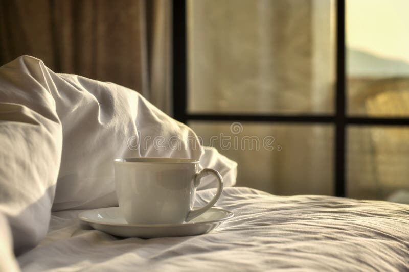 Taza del café con leche en una cama con sol de la ventana fotografía de archivo Taza del café con leche en una cama con sol de la ventana fotografía de archivo
