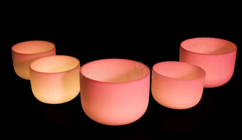 Crystal singing bowls with pink and red light on a dark background. Crystal singing bowls with pink and red light on a dark background