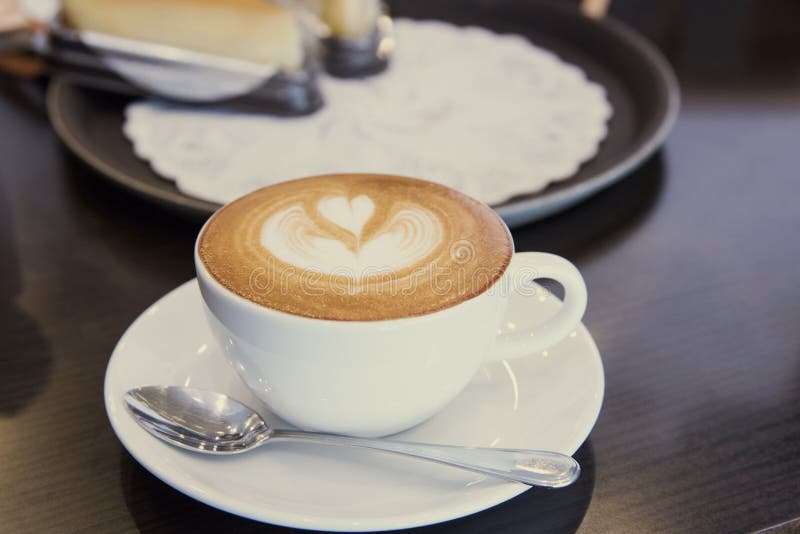 Tazza calda di arte del latte del caffè del primo piano sulla tavola di legno immagini stock libere da diritti Tazza calda di arte del latte del caffè del primo piano sulla tavola di legno immagini stock libere da diritti