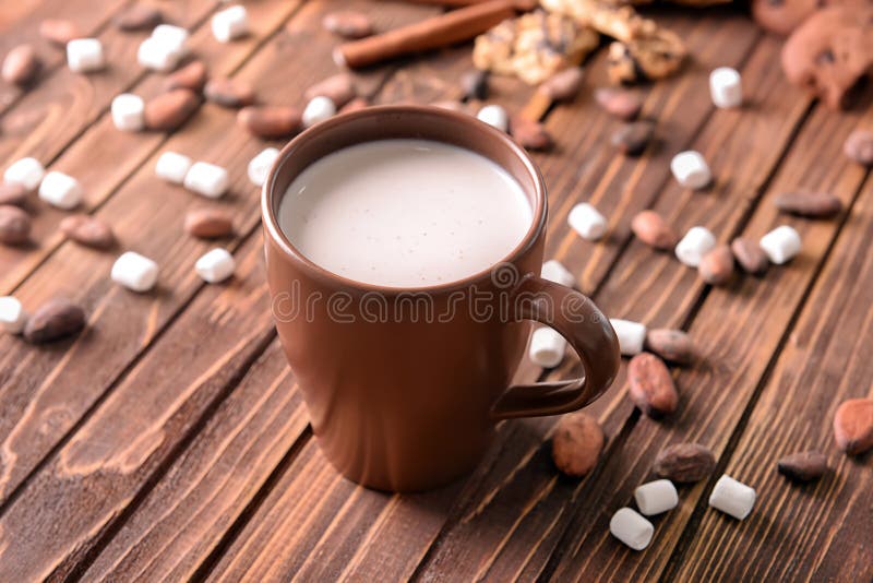 Tazza della bevanda deliziosa del cacao con le caramelle gommosa e molle ed i fagioli sulla tavola di legno fotografia stock libera da diritti Tazza della bevanda deliziosa del cacao con le caramelle gommosa e molle ed i fagioli sulla tavola di legno fotografia stock libera da diritti