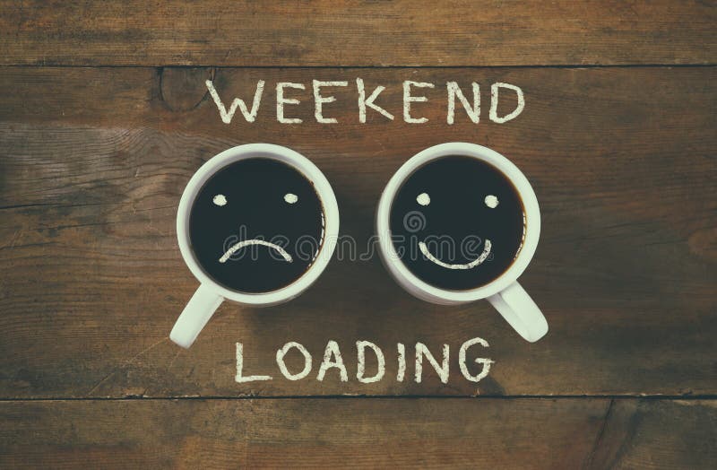 Coffee cup with sad and happy faces next to weekend loading phrase background. vintage filtered. happy weekend concept. Coffee cup with sad and happy faces next to weekend loading phrase background. vintage filtered. happy weekend concept.