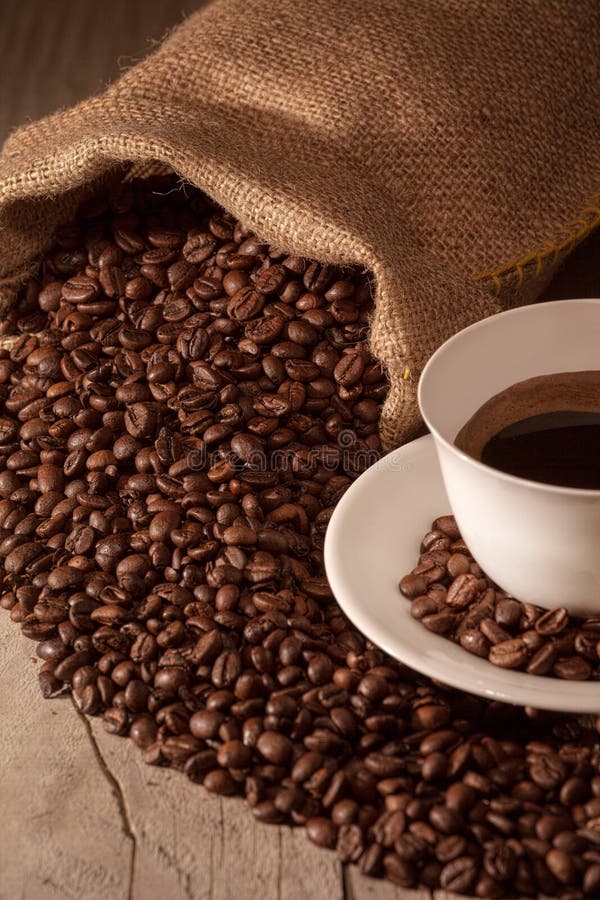Tazza di caffè con il sacco della tela da imballaggio dei semi di cacao torrefatti fotografia stock Tazza di caffè con il sacco della tela da imballaggio dei semi di cacao torrefatti fotografia stock