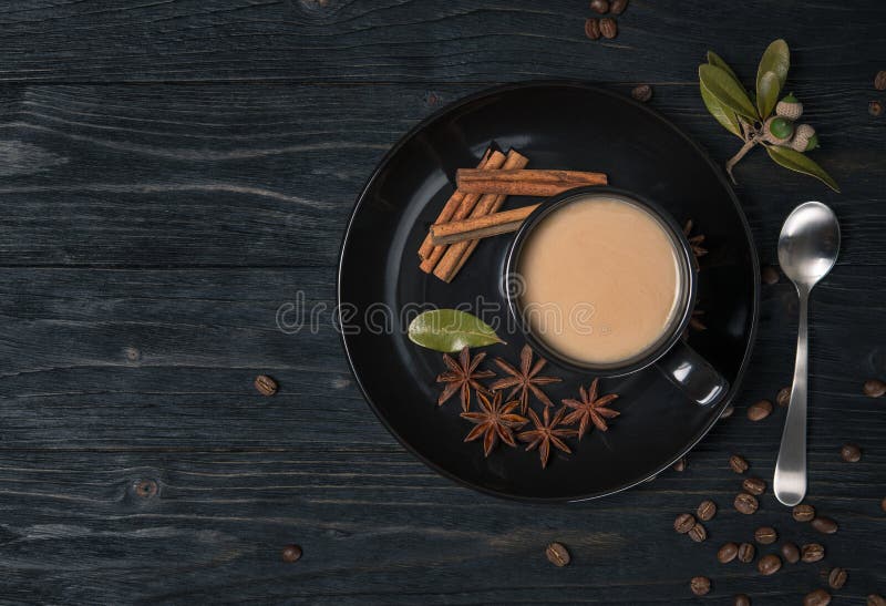 Tazza di caffè con latte. fango di cappuccino nero con ampolla decorata in lastra e bastoncini di cannella. chicchi di caffè. legn. tavola di legno naturale scuro. stagione autunnale. visualizzazione superiore a layout piatto con spazio di copia.