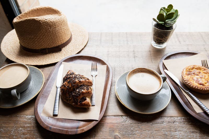 Tazza di caffè, di croissant fresco e di dessert locale su un tavolo in un caffè. fotografia stock libera da diritti
