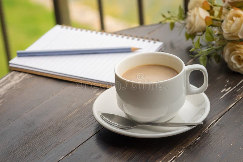 Tazza di caffè e taccuino aperto sulla tavola di legno fotografia stock