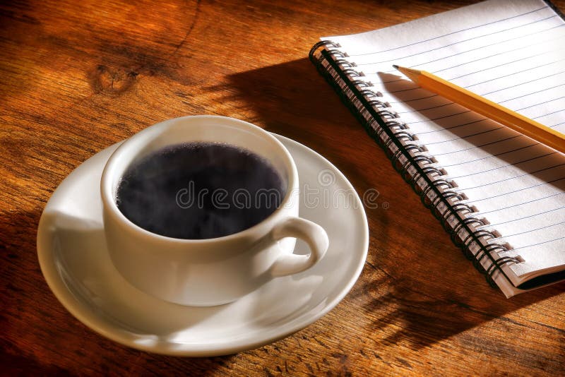 Tazza di caffè nero caldo con vapore ed il taccuino immagine stock
