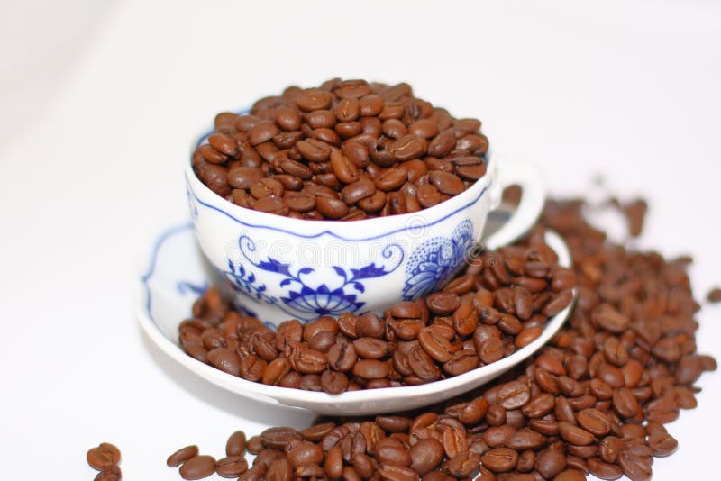 Tazza di porcellana con modello di cipolla pieno di chicchi di caffè fotografia stock