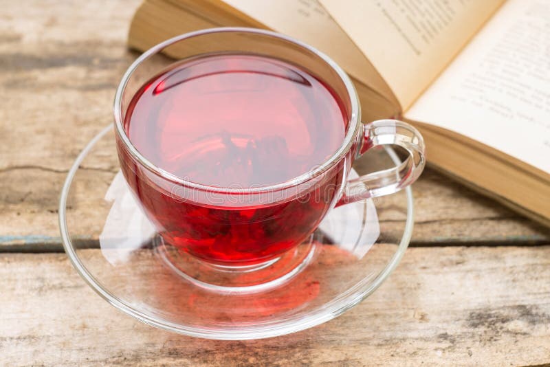 Tazza di vetro di tè caldo con il libro sulla vecchia tavola di legno fotografia stock Tazza di vetro di tè caldo con il libro sulla vecchia tavola di legno fotografia stock
