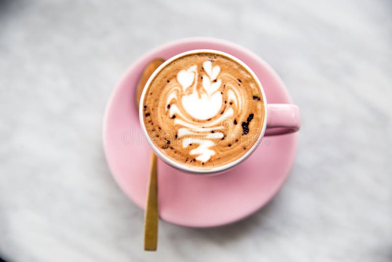Tazza rosa di cappuccino con arte del latte del cigno sul fondo di marmo della tavola fotografie stock libere da diritti Tazza rosa di cappuccino con arte del latte del cigno sul fondo di marmo della tavola fotografie stock libere da diritti