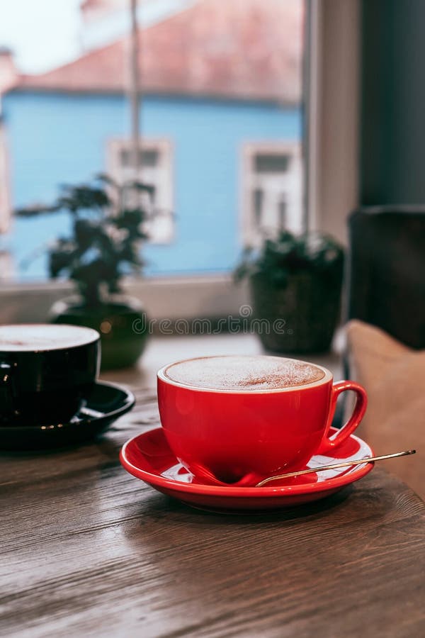 Tazze Di Ceramica Rosse E Nere Di Cappuccino Su Tavolo Di Legno in