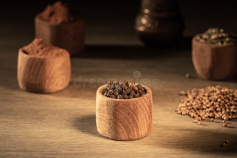 Tazze di legno con varie spezie su una tavola di contadini in legno immagini stock libere da diritti
