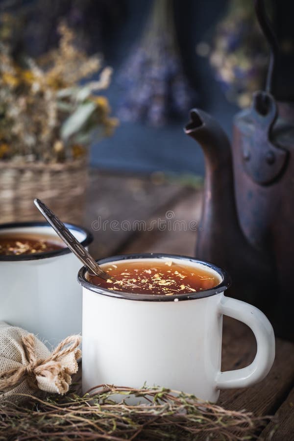 Tazze smaltate di tisana sana, del bollitore di tè e delle erbe curative fotografia stock Tazze smaltate di tisana sana, del bollitore di tè e delle erbe curative fotografia stock