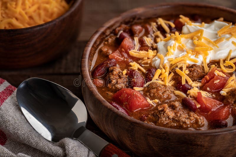 Closeup of bowl of chili con carne with shredded cheddar cheese and sour cream. Closeup of bowl of chili con carne with shredded cheddar cheese and sour cream