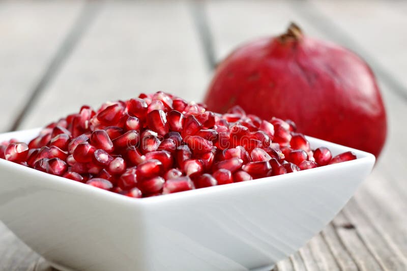 White bowl filled with pomegranate seeds. White bowl filled with pomegranate seeds.