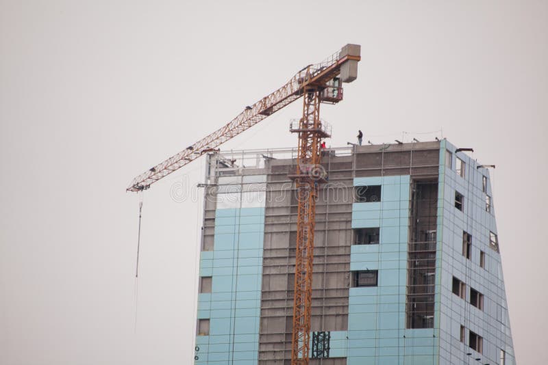 TBILISI, GEORGIA - FEBRUARY 19, 2016: building a skyscraper with the builders on the roof stock photos TBILISI, GEORGIA - FEBRUARY 19, 2016: building a skyscraper with the builders on the roof stock photos