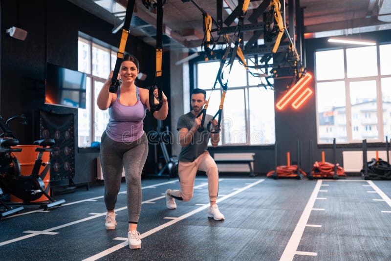 Te zware vrouw die positief terwijl het uitoefenen met TRX voelen royalty-vrije stock foto's Te zware vrouw die positief terwijl het uitoefenen met TRX voelen royalty-vrije stock foto's