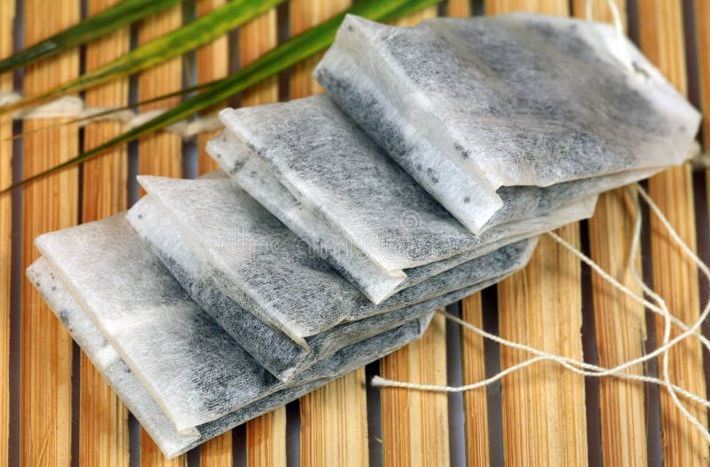 Tea bags stacked on wooden background.