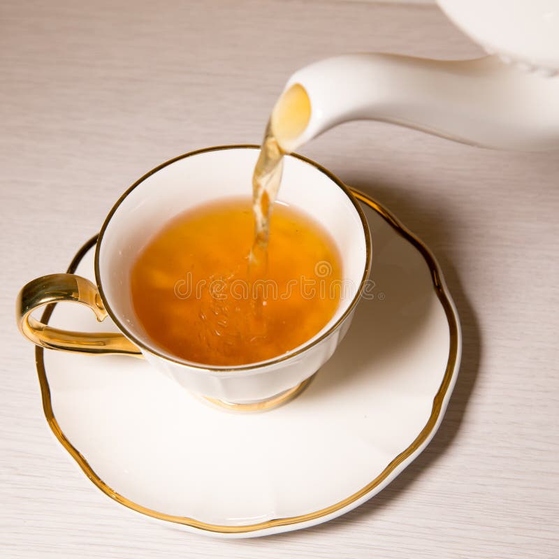 Tea Being Poured into Tea Cup, on White Background. Stock Photo Image
