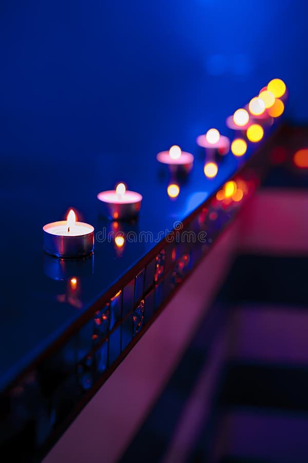 Tea Candle and Defocused Candle Lights on Blue Background Stock Photo